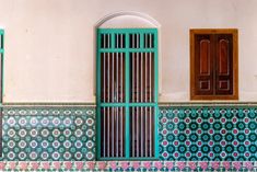 an old building with green doors and decorative tiles on the outside, along with a wooden window