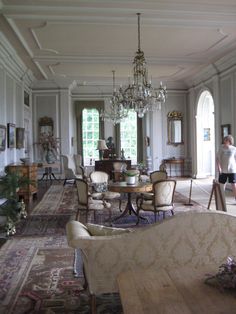 a living room filled with lots of furniture and a chandelier hanging from the ceiling