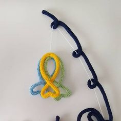 two crocheted objects are hanging next to each other on a white table top