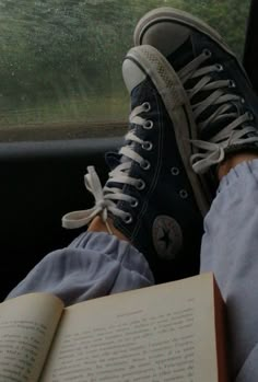 a person sitting in the back seat of a car with their feet on an open book