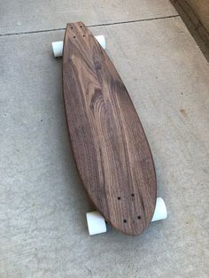 a wooden skateboard sitting on top of a cement floor next to a sidewalk with white wheels