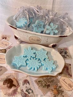 snowflake cookies are in a bowl on a table with pictures and tags around it