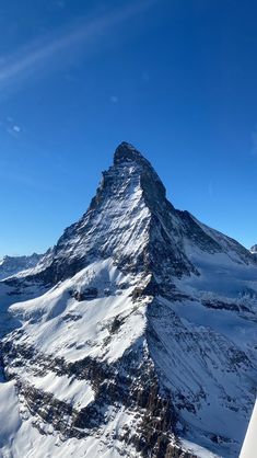 a very tall mountain covered in snow under a blue sky