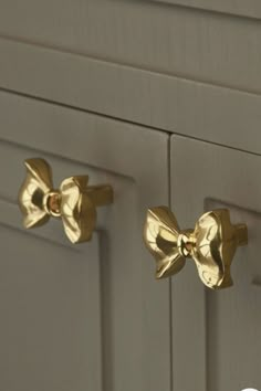 two gold bow knobs on the front of a gray cabinet