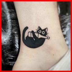 a small black cat tattoo on the ankle