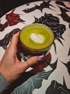 a hand holding a cup filled with green liquid