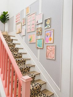 there is a staircase with pictures on the wall and pink handrails in front of it