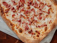 a pizza sitting on top of a pan covered in cheese and bacon toppings,