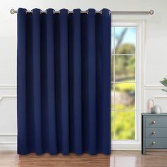 a blue curtain hanging in front of a window with wood flooring and white walls