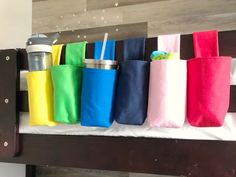 a row of colorful bags sitting on top of a wooden bed next to a wall