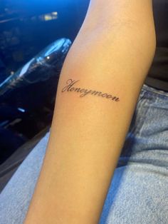 a woman with a tattoo on her arm that reads,'honeymoon'in cursive writing