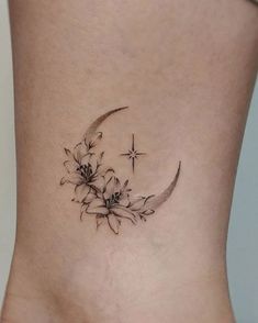 a small tattoo on the side of a woman's lower body, with flowers and a crescent moon