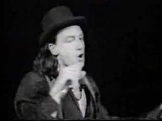 a man in a suit and hat singing into a microphone