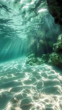 an underwater view of the water with sunlight coming in from behind it and some rocks