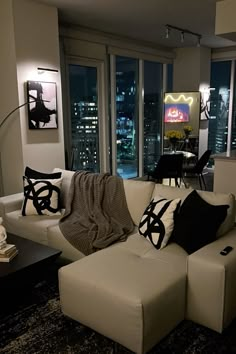 a living room filled with furniture and large windows overlooking the city lights at night time