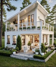 a white house with lots of windows and balconies on the top floor is surrounded by greenery