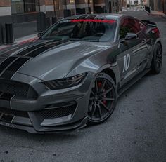 a gray mustang parked in front of a tall building