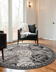 a black and white rug in a living room next to a chair with pillows on it