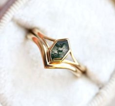 a gold ring with a green tourmaline stone in the center on a white cloth