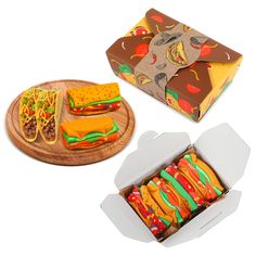 two open boxes with sandwiches in them on a wooden platter next to a cardboard box