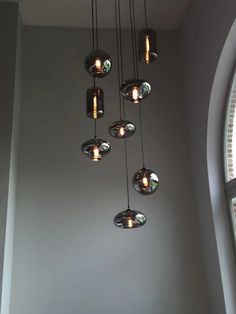 a chandelier hanging from the ceiling in front of a window with several lights on it