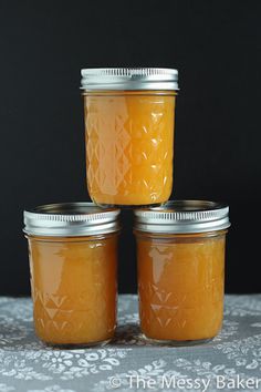 three jars filled with orange jam sitting on top of a table