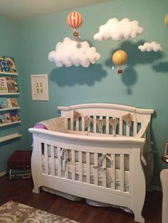 a white crib in a blue room with hot air balloons