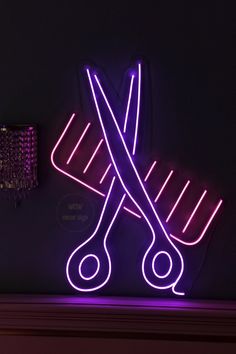 a pair of scissors sitting on top of a table next to a lamp with purple lights