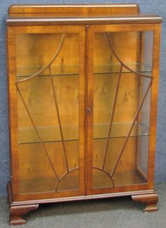 an antique display cabinet with glass doors and wood trimmings on the top shelf