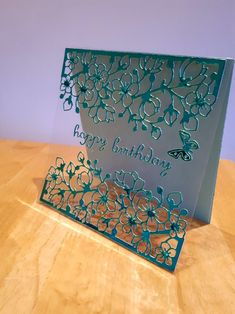 a birthday card with flowers and butterflies on the front, sitting on a wooden table