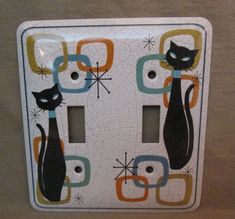 a decorative light switch cover with two black cats on it's side and an orange, blue, green, yellow, and white design