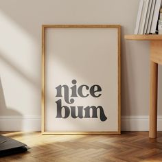 a framed poster with the words nice bum on it in front of a wooden table