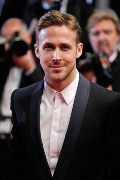 a man in a tuxedo is posing for the camera with cameras around him