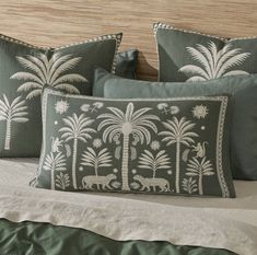 a bed topped with two pillows and palm trees