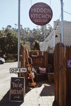 a sign for the hidden kitchen in front of a fenced off area with signs on it