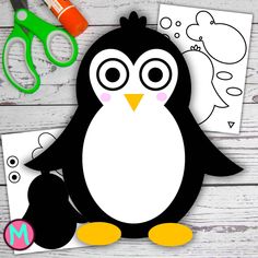 a penguin cut out next to scissors and other crafting supplies on a wooden table