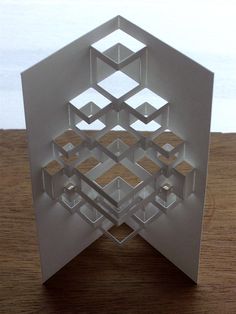 an abstract paper sculpture sitting on top of a wooden table