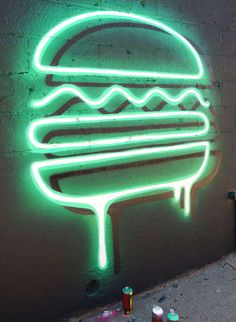 a neon sign on the side of a building that has a large hamburger painted on it