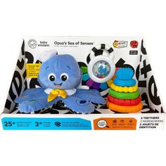 a blue stuffed animal sitting next to a stack of colorful toy items in a box