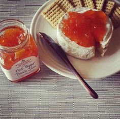 a plate with crackers and jam on it next to a jar of peanut butter