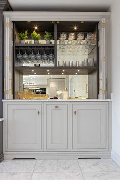 a kitchen with marble floors and white walls, along with an open cabinet filled with glassware