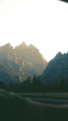 the mountains are covered with snow in the early morning hours as seen from inside a moving vehicle