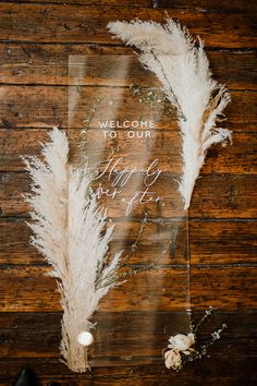 the welcome sign is placed next to some white flowers and pamolite on a wooden table