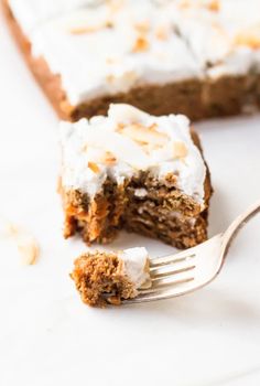 a piece of carrot cake with frosting on top and a fork in the foreground