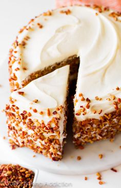 a carrot cake with white frosting and sprinkles on a white plate