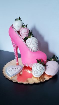 a pink shoe cake with white frosting and strawberries on top