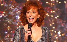 a woman holding a microphone in front of fireworks