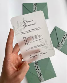 a person holding up a business card in front of green envelopes with leaves on them