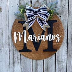 a wooden sign with the word marinanos on it and a bow hanging from it