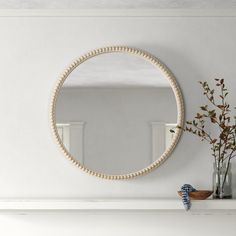 a white fireplace with a round mirror on the mantle